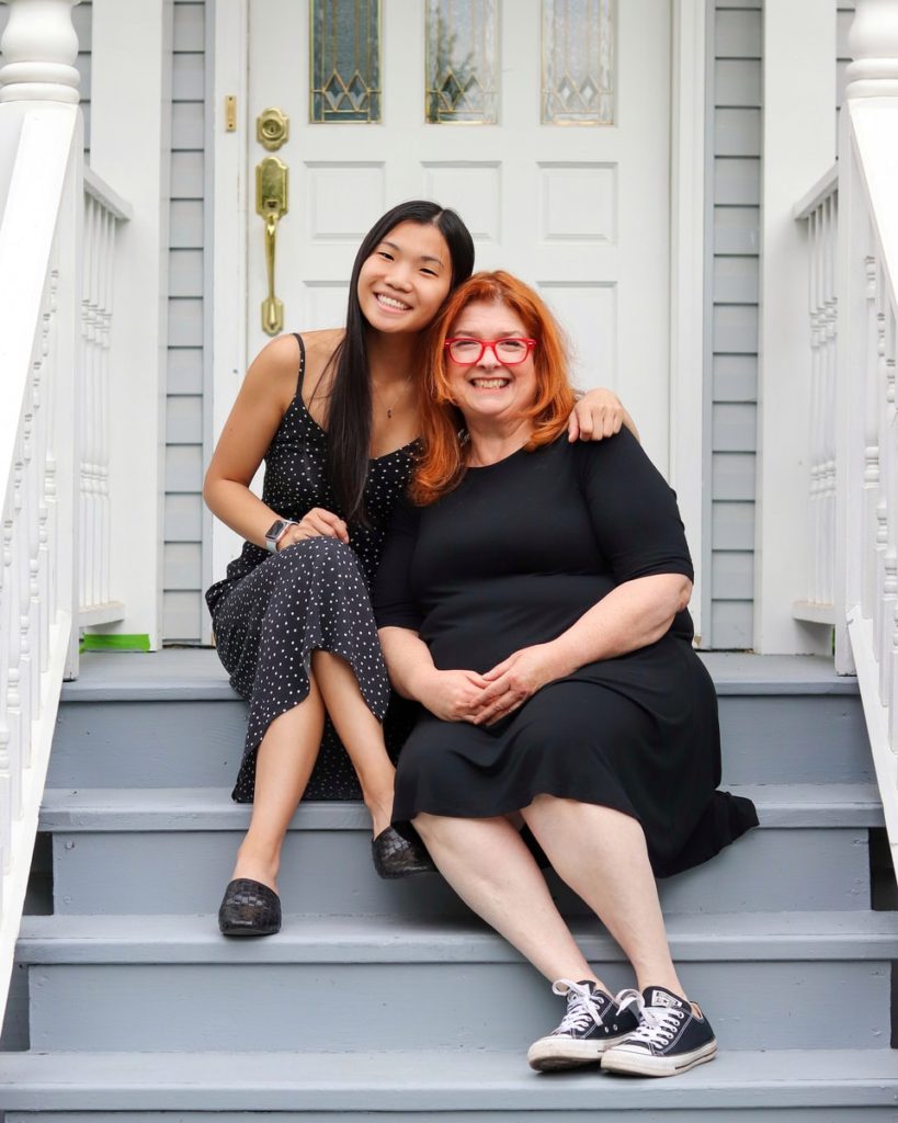 2 women sitting on white wooden bench